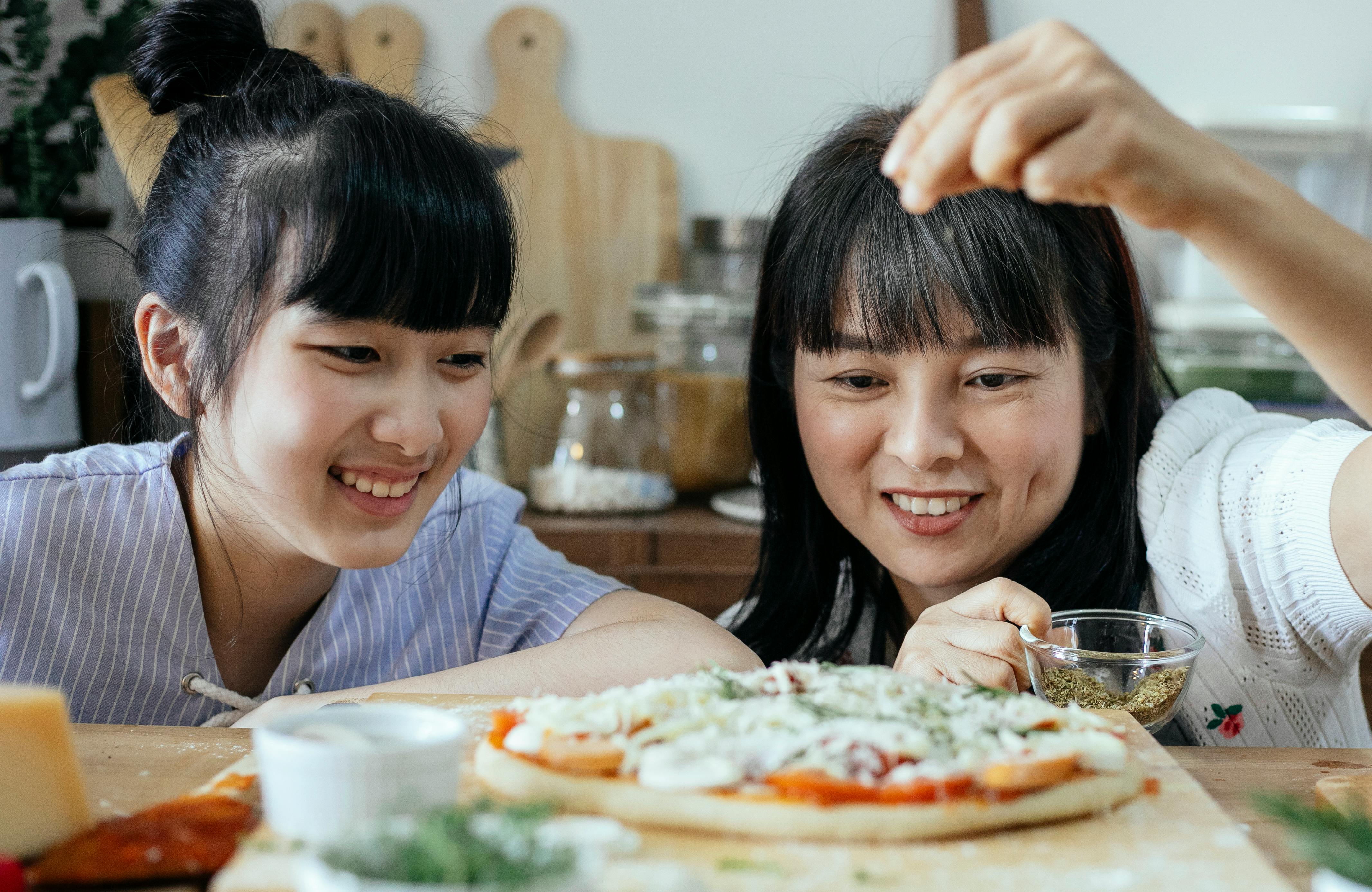 Women happily baking pizza in the kitchen